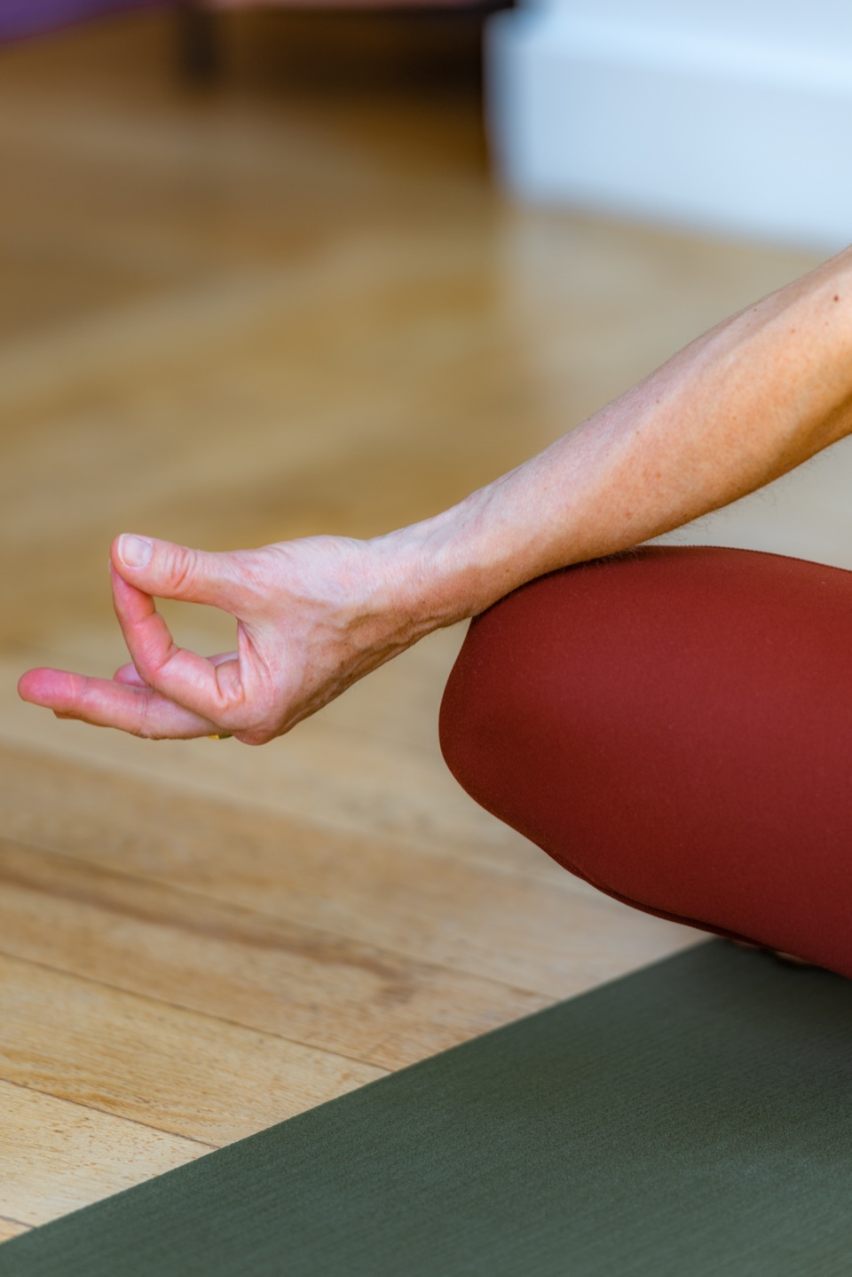 Gros plan d'une main posée en mudra sur le genou, pendant un temps de méditation assise
